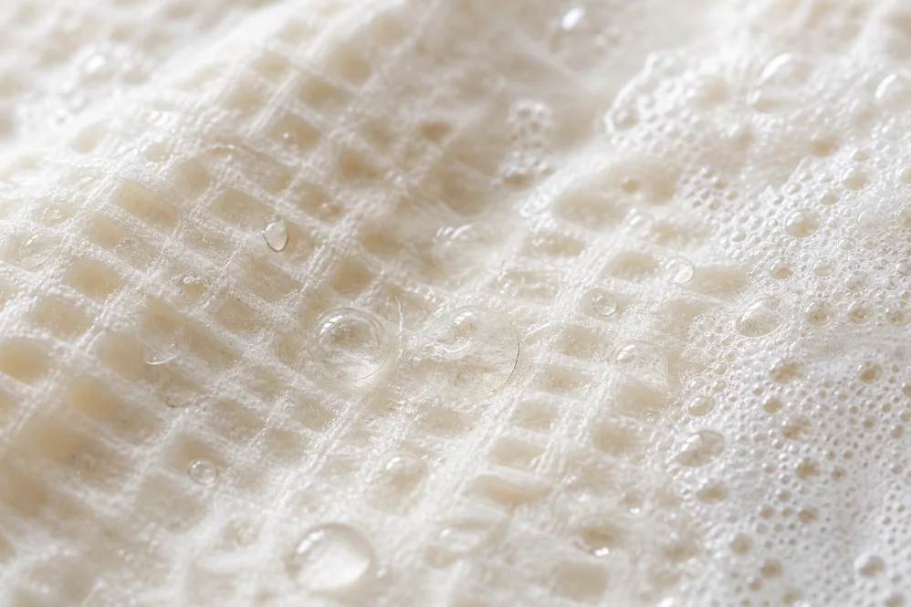macro of a sudsy softened bare. sheet bloomed into a foamy scrub texture